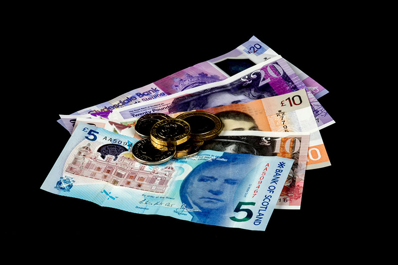 Scottish banknotes with coins isolated on a black background